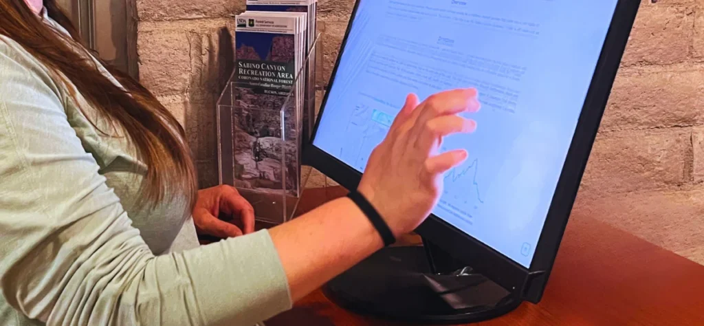 A woman's hand using a touch screen monitor.